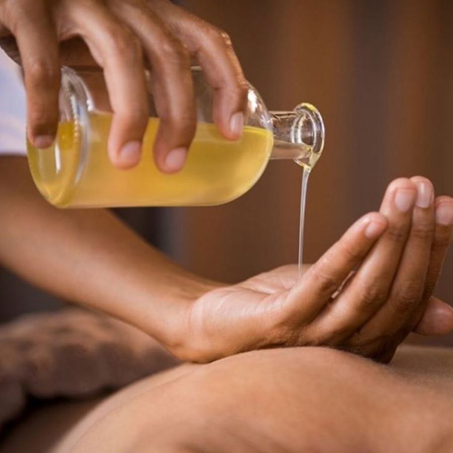 Warm massage oil poured into a therapist's hands